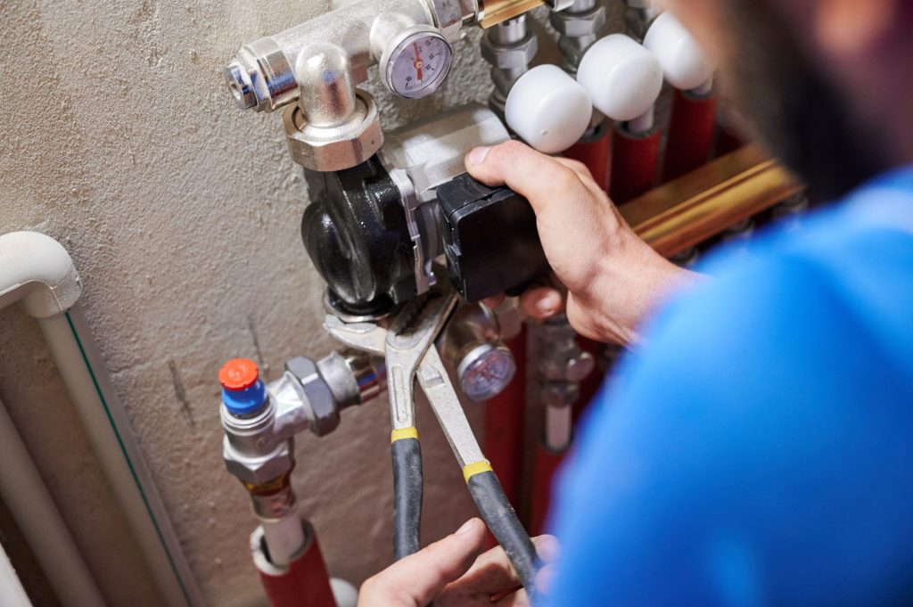 Plumber installing a pump using wrenches